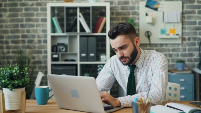 man sitting and working on laptop at office