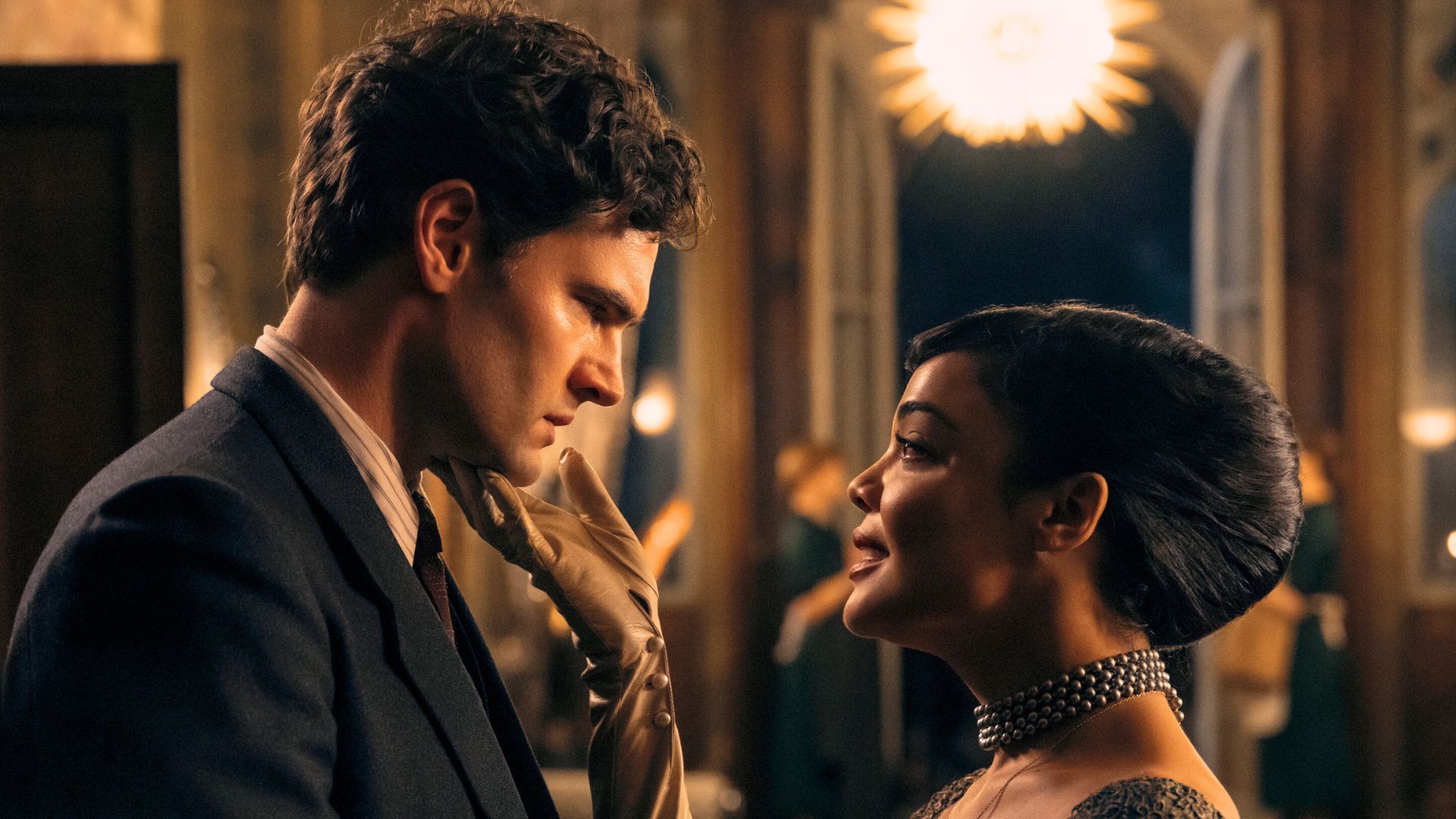 Tessa Thompson holds Tom Bateman's chin in a gloved hand