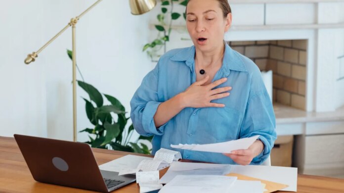 A woman at a desk letting out a deep sigh.