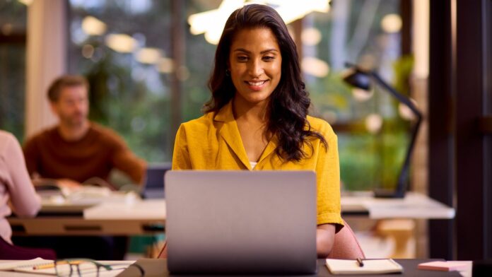 A young woman is working on a Windows 10 laptop and looking happy