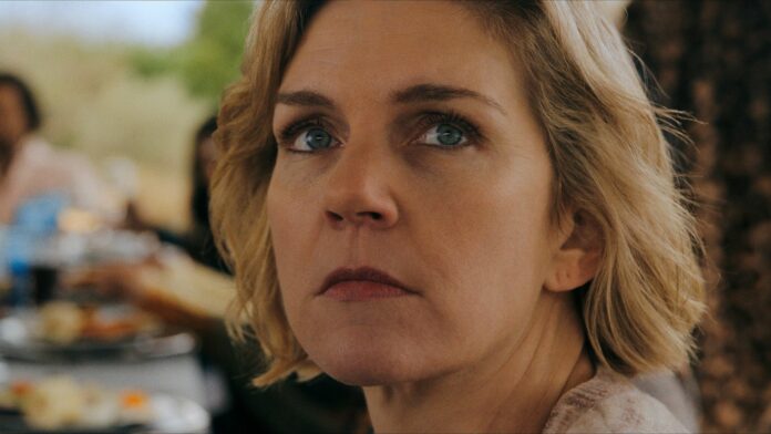 A close up of Carol looking at someone standing off-camera in Pluribus episode 2