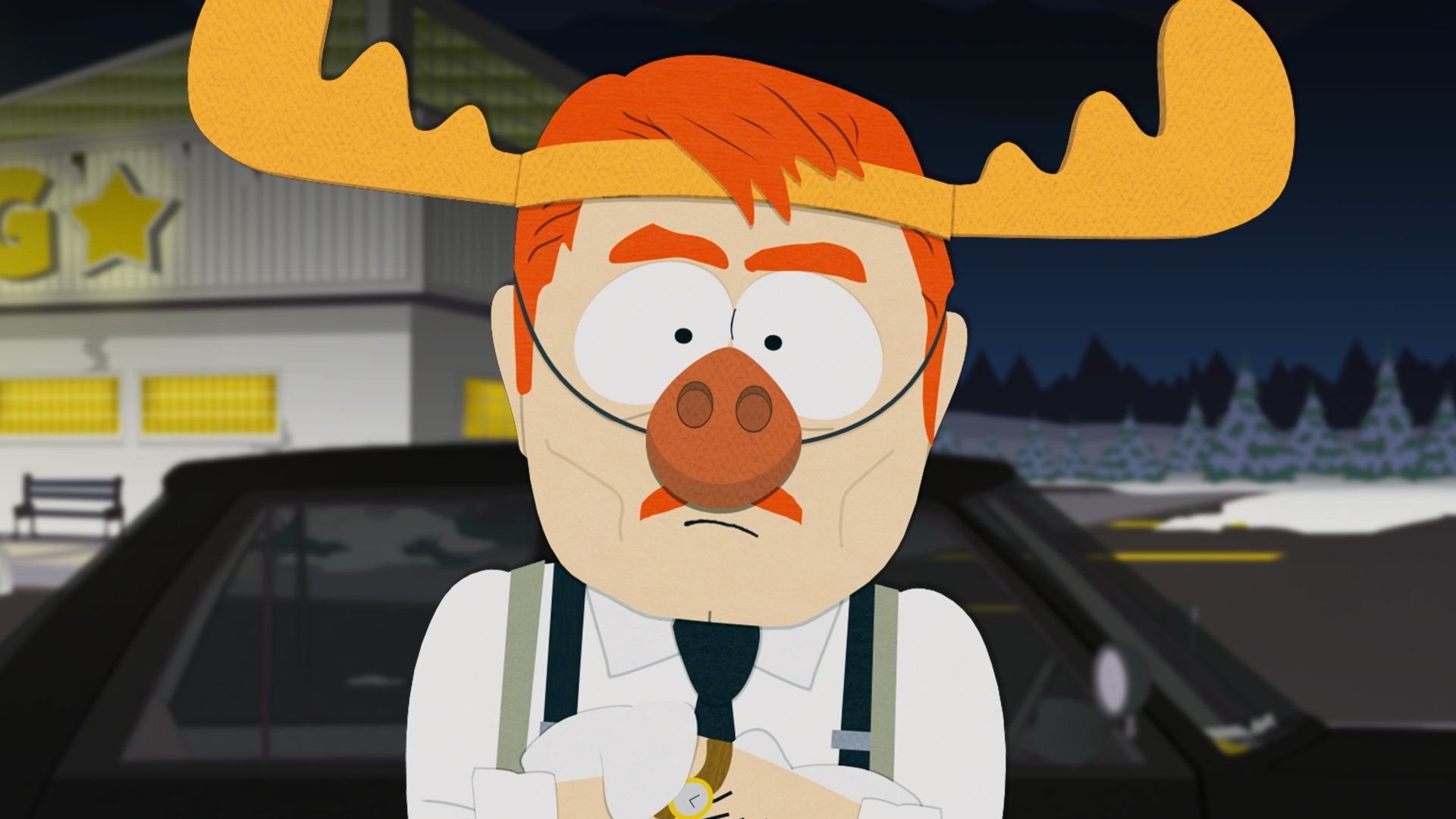 A ginger man wears a suit and a reindeer's horns and nose