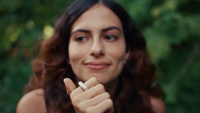 A woman with her right hand raised to her chin, with a silver ring on her index finger.