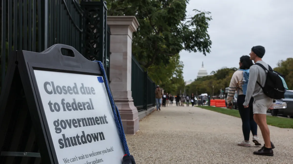 Government shutdown sign with people walking.