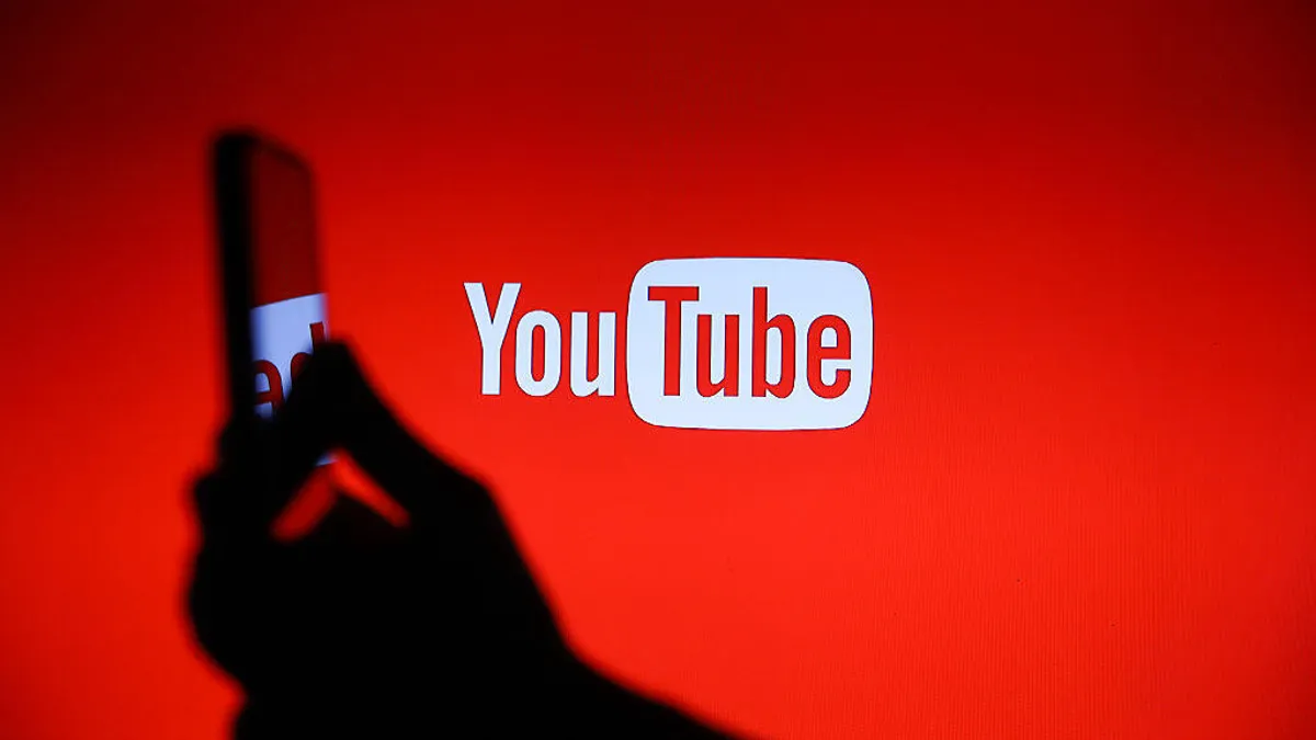 YouTube logo brightens a hand holding a dimmed cell phone.